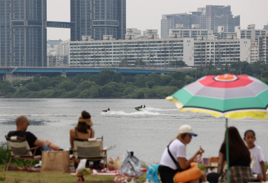 흐리고 다소 더운 날씨가 찾아온 23일 오후 반포 한강공원을 찾은 시민들이 강가에서 더위를 식히고 있다. 연합뉴스